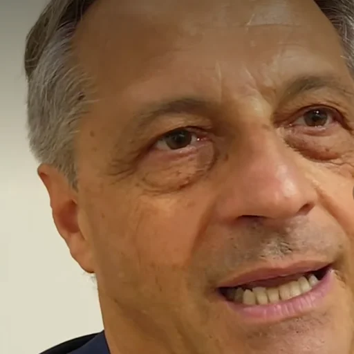 Fotografia di Bruno Speranza: ritratto ravvicinato mentre parla al microfono durante un'intervista, giacca blu e camicia rigata