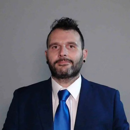 Fotografia di Luigi Garone: ritratto frontale a mezzo busto, giacca blu scura, camicia bianca e cravatta blu
